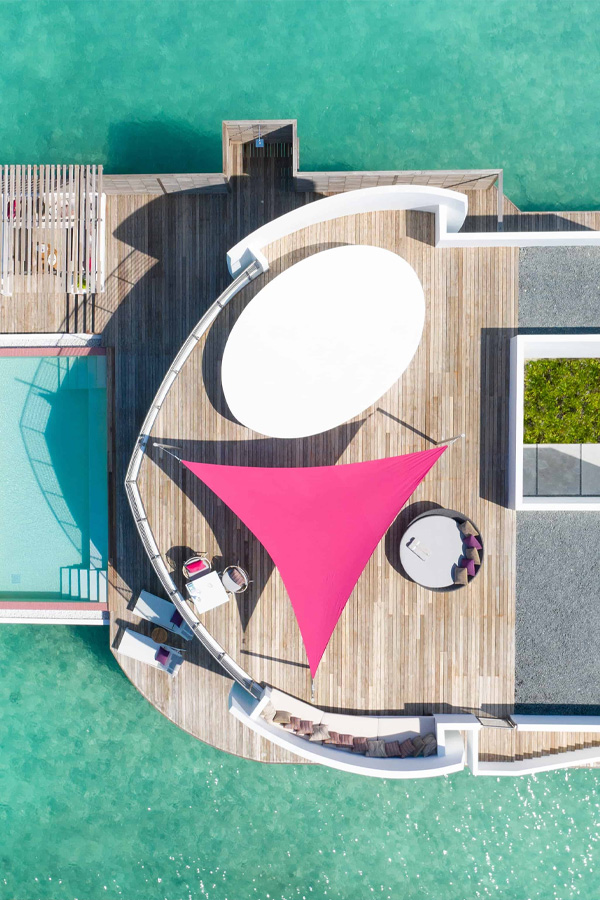 Vue d'en haut d'une terrasse en forme de bateau avec une toile tendue rose et une table blanche